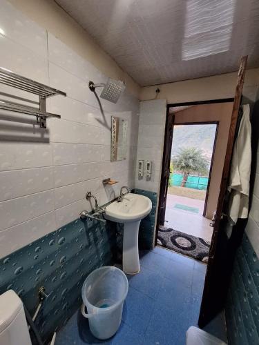 a bathroom with a toilet and a sink and a door at Valley King Resort in Rishīkesh