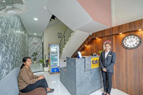 インドールにあるFabHotel Cressidaの時計付きロビーに立つ二人