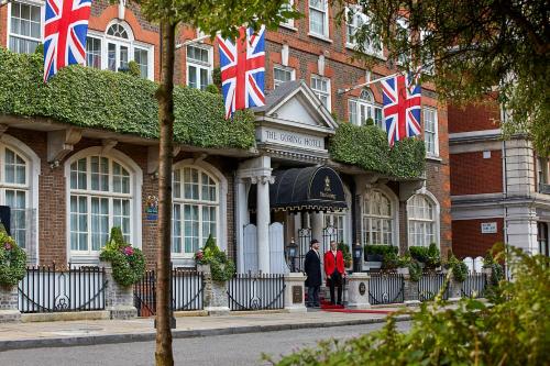 a group of people standing outside of a building with british flags at The Goring in London