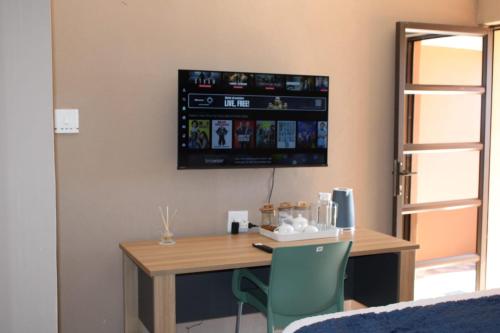 Royal Gidlas Guesthouse في Saulspoort: غرفة مع طاولة وتلفزيون على الحائط