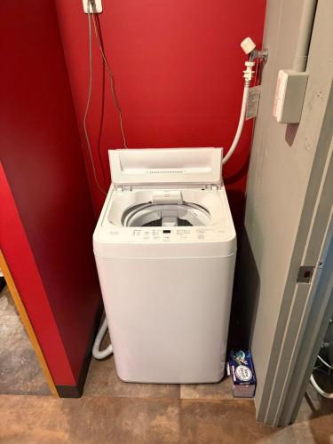 a washing machine in a room with a red wall at oak HOUSE in Matsuyama