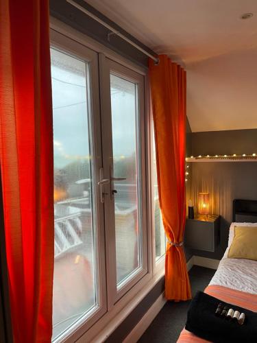 a bedroom with a large window with red curtains at Reggae Beach Getaway in Saltdean
