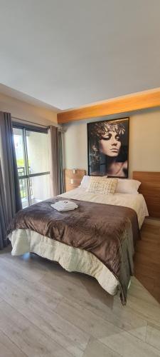 a bedroom with a large bed with a poster on the wall at Nany Vitrali Moema in São Paulo
