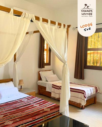 a bedroom with two beds and a canopy at Sahara Lounge in Tozeur