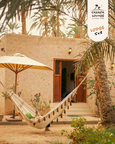 a hammock and an umbrella in front of a house at Sahara Lounge in Tozeur