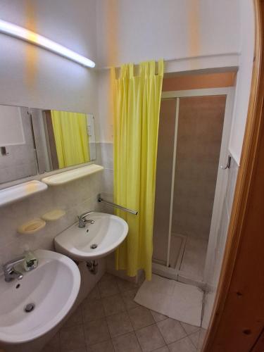 a bathroom with a sink and a shower with a yellow shower curtain at Tau Forest Lodge in Solkan