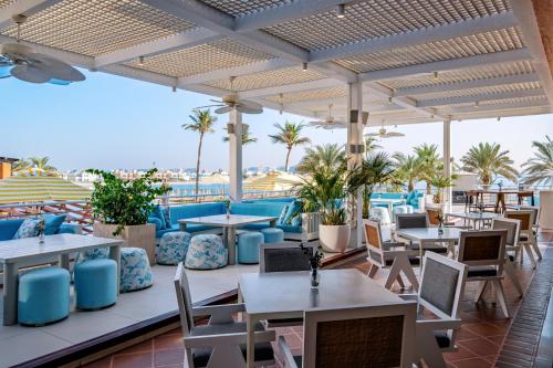a restaurant with tables and chairs and palm trees at Andaz Dubai The Palm, By Hyatt in Dubai