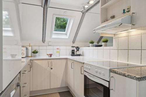 a kitchen with white cabinets and a window at Feriehus 1133 in Ringkøbing