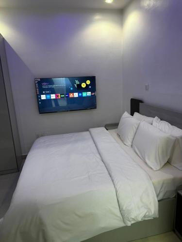 a bedroom with a white bed with a tv on the wall at Modern 3-Bedroom Luxury Home in Lekki Phase 1 in Lekki