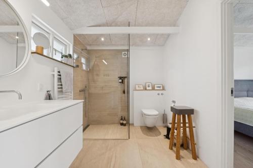 a bathroom with a shower and a toilet and a stool at Feriehus 1142 in Ringkøbing