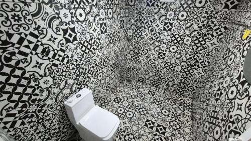 ein Badezimmer mit einem schwarz-weißen Duschvorhang und einer Toilette in der Unterkunft Zeno Village Resort 900 Kandi Wayanad in Wayanad