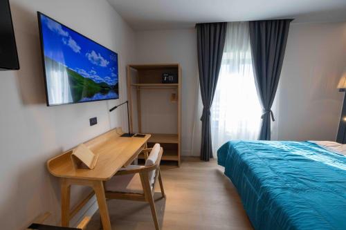 a hotel room with a desk and a bed and a television at Gran Suite Darsena in Isola Sacra