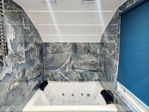 een badkuip in een badkamer met een schilderij aan de muur bij Hotel London in Londen