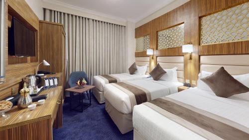 a hotel room with two beds and a television at Al Ansar Platinum Hotel فندق الأنصار بلاتينوم in Medina
