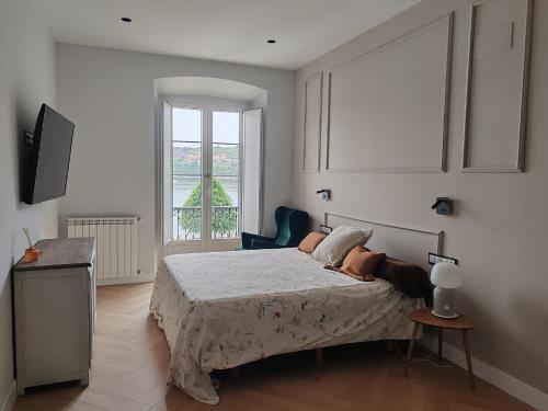 a white bedroom with a bed and a window at alojamiento Premium Ribadesella Vistas al Mar in Ribadesella