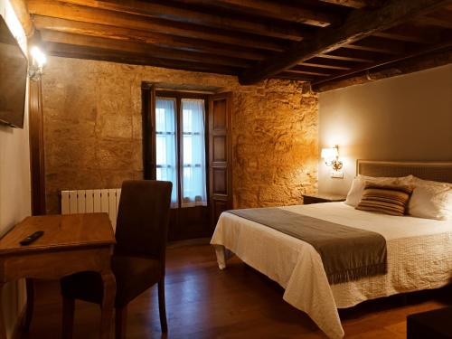 a bedroom with a bed and a desk and a window at Hotel Vila As Pedras in Roxos