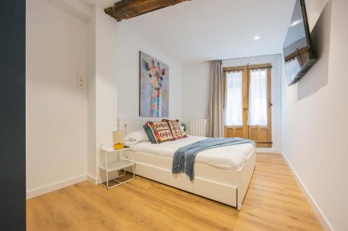 Una habitación blanca con una cama y una ventana en Plaza Nueva, en Bilbao