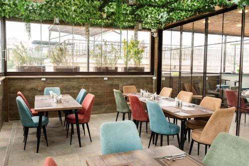 a restaurant with tables and chairs and windows at Parliament Hotel & Restaurant in Baku