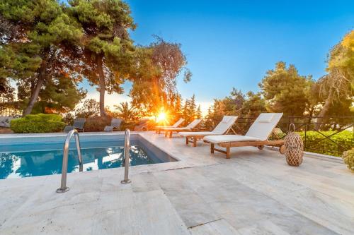 a swimming pool with lounge chairs next to a swimming pool at Seaview Villa Cleopatra - Private Pool & Tennis Court in Kalamos