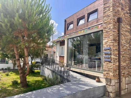 a house with a tree in front of a building at Hostel do Alto - Fão in Esposende