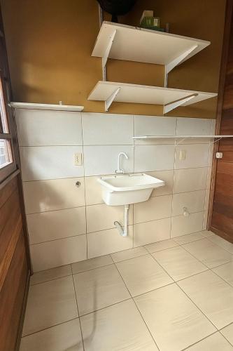 a white bathroom with a sink and shelves at Pousada Astral in Imbituba