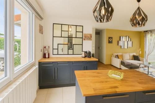 une cuisine avec des armoires bleues et un salon dans l'établissement Maison Chardonnerets - Poitiers, à Biard