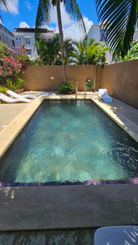 una piscina en un complejo turístico con palmeras en Theresa Apartments Mauritius, en Trou aux Biches