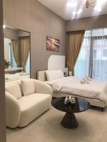 a living room with a couch and a bed and a table at Luxury Furnished Studio with Alexa Automation JVC in Dubai