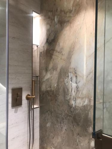 a shower in a bathroom with a stone wall at Luxury Furnished Studio with Alexa Automation JVC in Dubai
