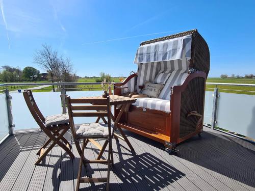a rocking chair and a table on a deck at Deichkoje in Westerdeichstrich