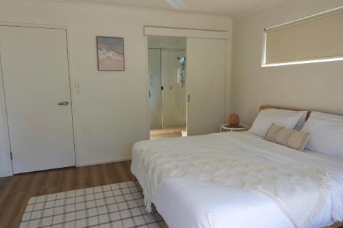 a bedroom with a large white bed and a shower at Ocean Aura Room A in Airlie Beach