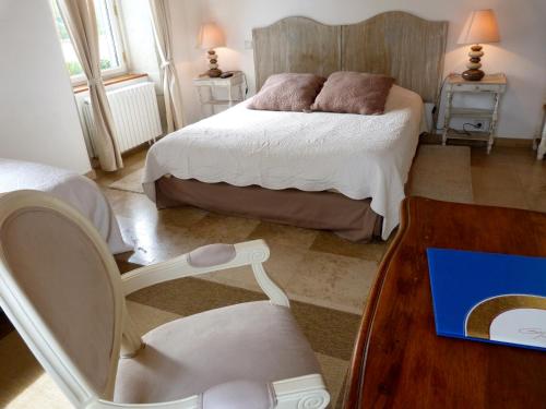 a bedroom with a bed and a chair and a table at Domaine du Manoir in Les Avenières