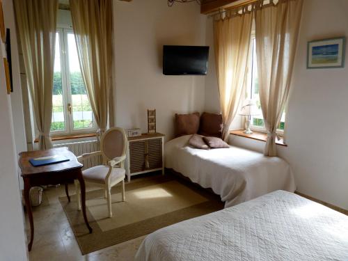a bedroom with two beds and a desk and a tv at Domaine du Manoir in Les Avenières