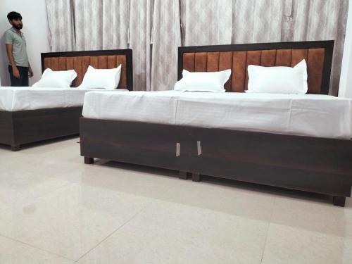 two twin beds in a room with a man standing between them at jp hotel and restorent in Rīngas