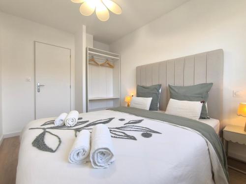 Les Dunes - Calme et Sérénité à 5 min de la Plage en voiture في Biville-sur-Mer: غرفة نوم بها سرير أبيض كبير مع مناشف عليه