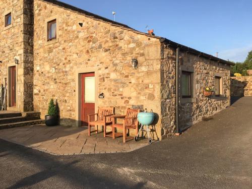 Horseshoe Cottage في Bolton by Bowland: طاولة وكراسي خارج مبنى حجري