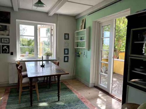 BorreにあるCosy Holiday Home In Møns Natureの木製のテーブルと2つの窓があるダイニングルーム