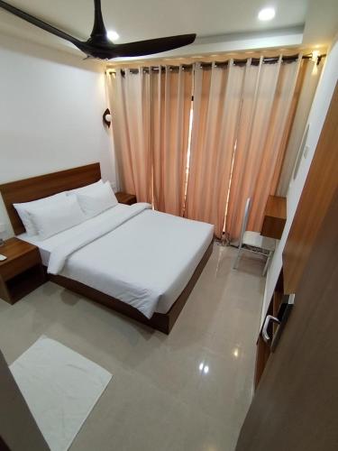 a bedroom with a white bed and a large window at Handhuveli Dhangethi in Dhangethi