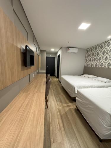 バウネアーリオ・コンボリウーにあるHotel das Américasのベッド2台と薄型テレビを備えたホテルの部屋