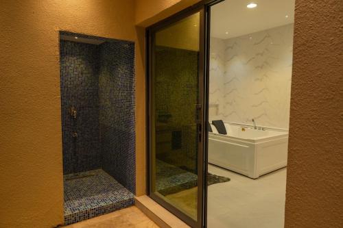 Un baño con ducha de cristal, bañera y lavabo. en Private Home Gardens & Pools, Complementary tours and experiences inclusive, en Murayjāt