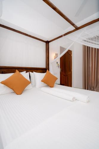 a bedroom with a white bed with orange pillows at Scenery River Star Hotel in Hikkaduwa