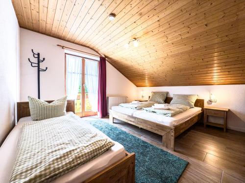 a bedroom with two beds and a wooden ceiling at Landhaus Steibis in Steibis