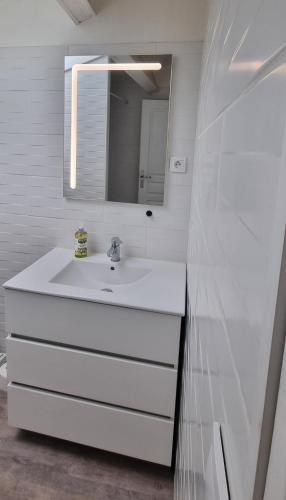 a white bathroom with a sink and a mirror at Maison proche Grand Parc 2 Chambres in Mauléon