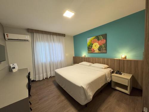 een slaapkamer met een bed en een schilderij aan de muur bij Hotel das Américas in Balneário Camboriú