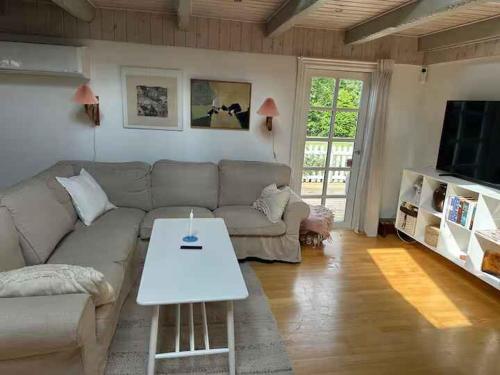 a living room with a couch and a table at Holiday Home With Outdoor Pool, Great Location in Hornsved