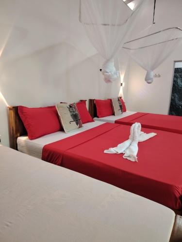a room with two beds with red and white sheets at Peacock's Paradise Safari Hostel in Udawalawe