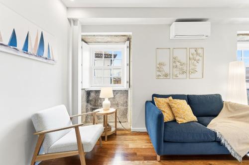 GuestReady - Charming Porto Retreat Near the Sea في بورتو: غرفة معيشة مع أريكة زرقاء وكرسي