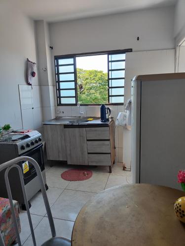 a kitchen with a table and a sink and a window at Apartamento Larah in Cianorte