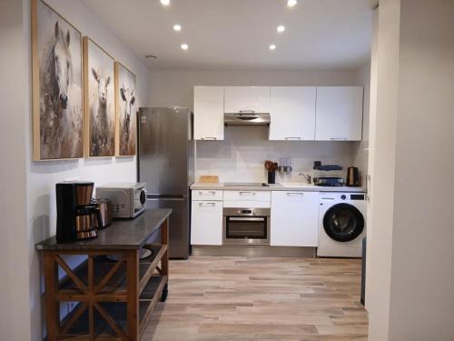 eine Küche mit weißen Schränken und einem Kühlschrank in der Unterkunft Escapade Champêtre in Saint-Martin-en-Bière