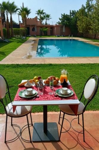 a table with a plate of food next to a pool at Villa Essalah & Spa Marrakech in Marrakech